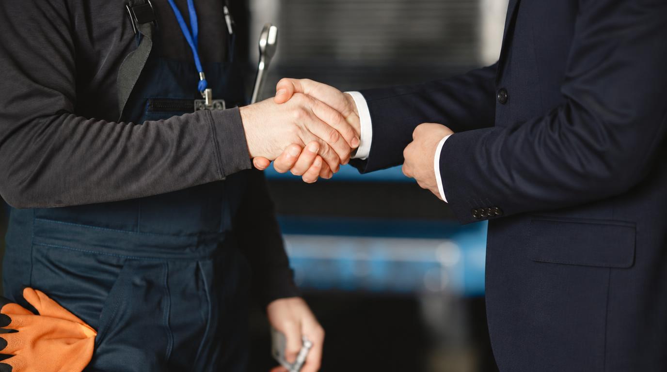 Poignée de main entre un artisan en tenue de travail et un repreneur en costume : la transmission d'une entreprise — Alexis Schumacher, repreneur